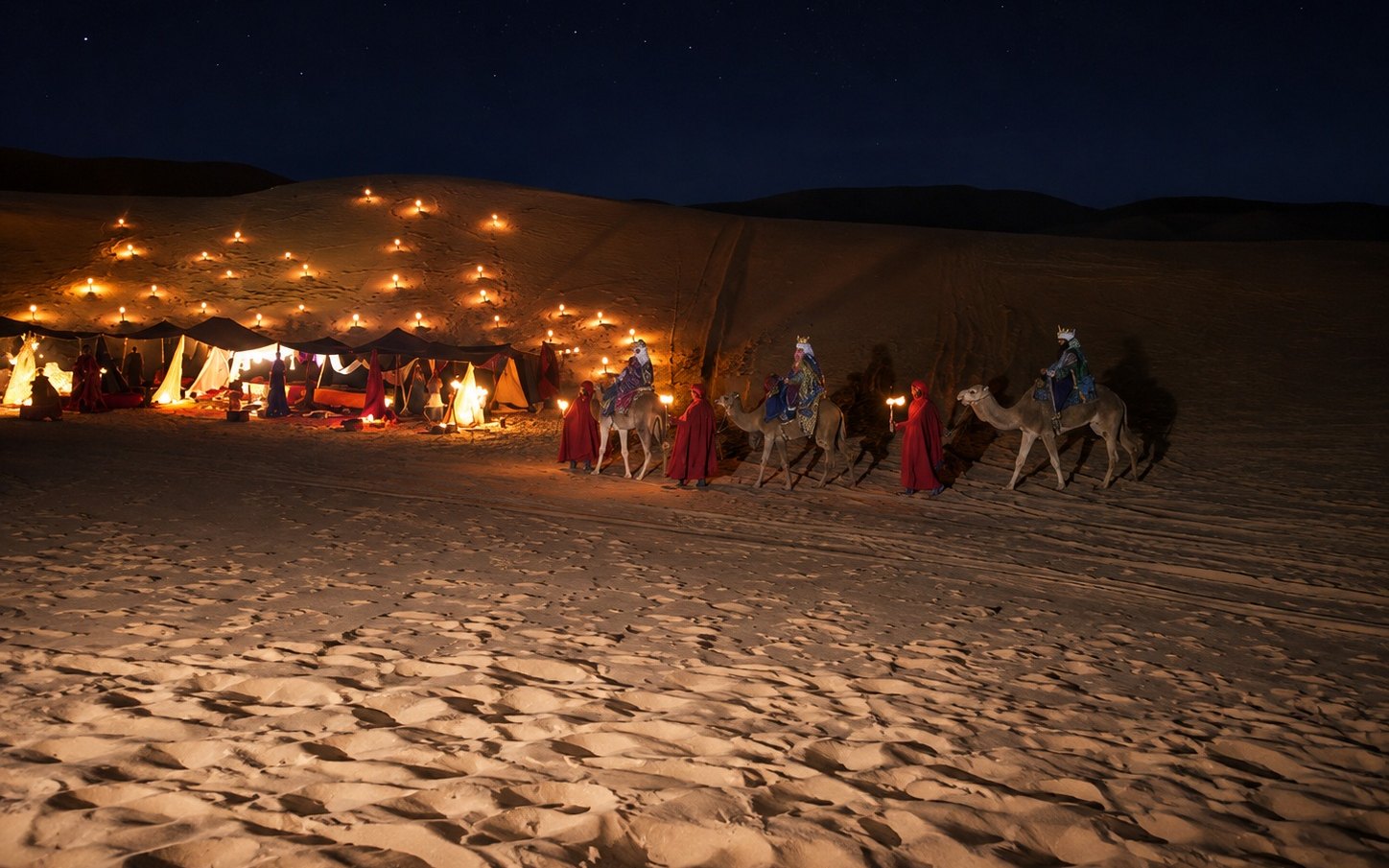 El campamento de los Reyes Magos iluminado con cientos de velas en la duna